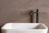 Terrazzo Granitech resin microtopping on bathroom wall in taupe finish with marble sink.