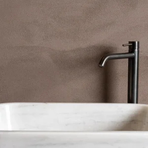 Terrazzo Granitech resin microtopping on bathroom wall in taupe finish with marble sink.